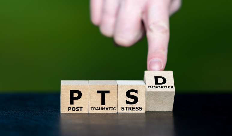 Person touching wooden blocks that say PTSD
