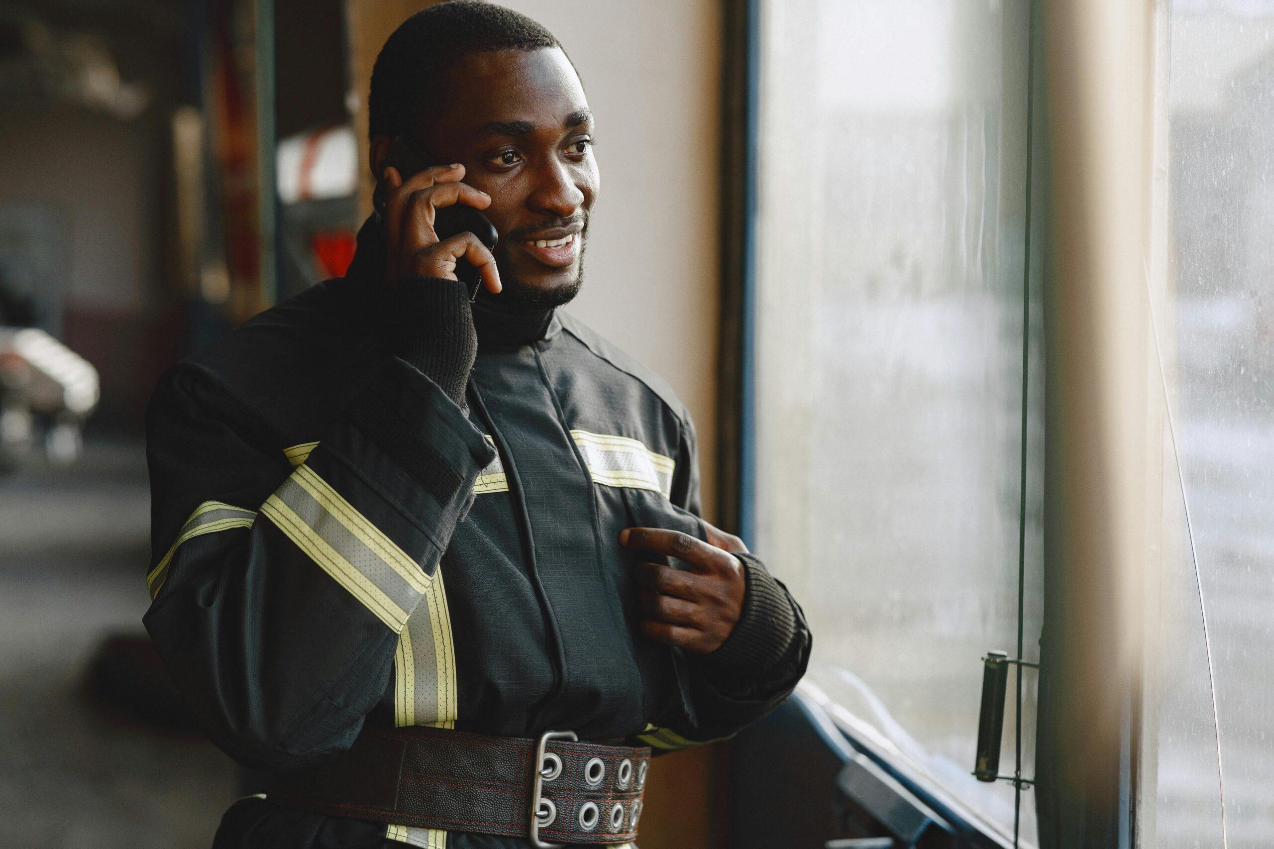 Firefighter talking on a cell phone while standing by a window